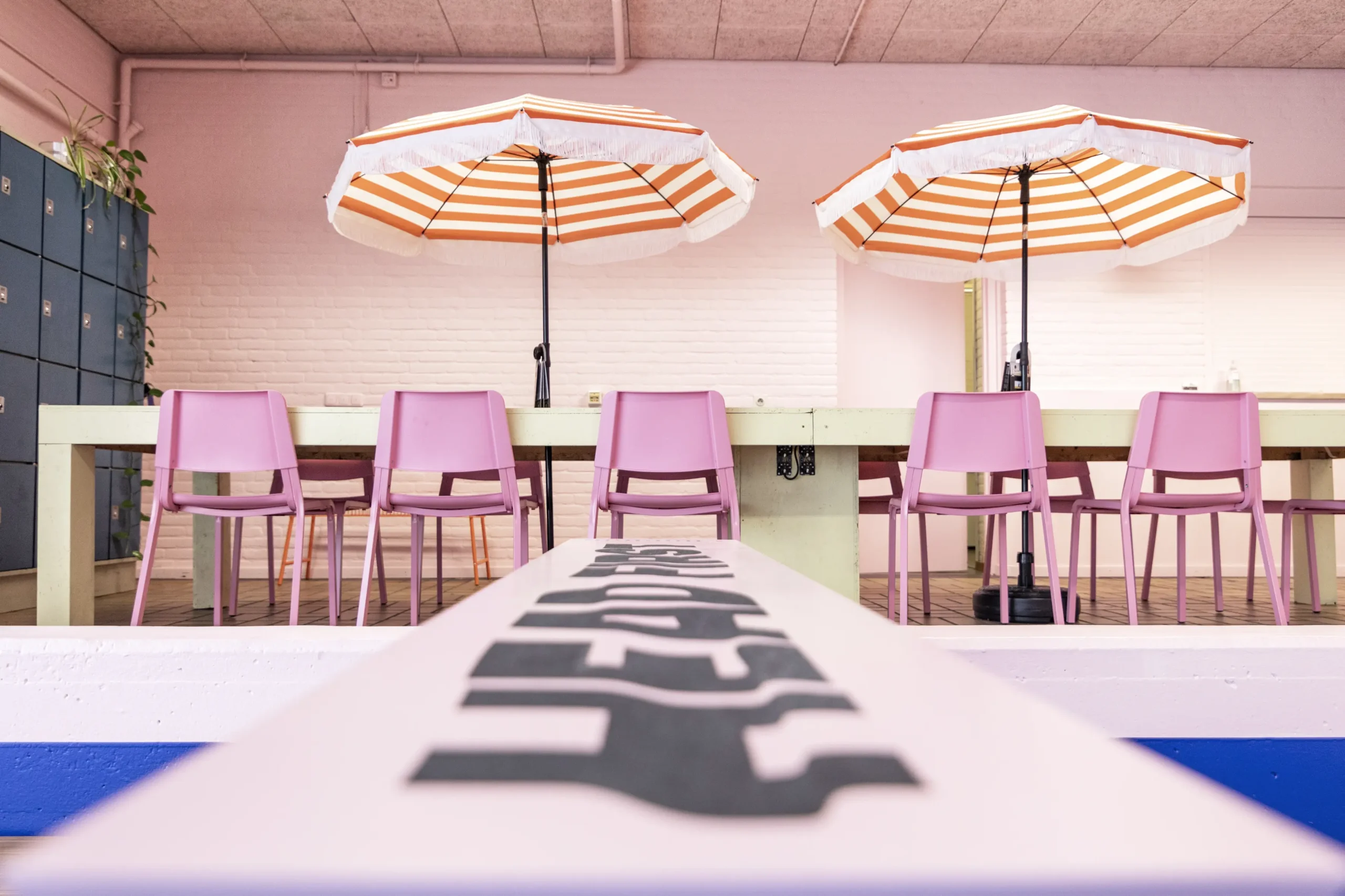 vergaderruimte-co-zwolle-ina-vrinssen tafel met roze stoelen en kleurrijke parasols in vergaderruimte